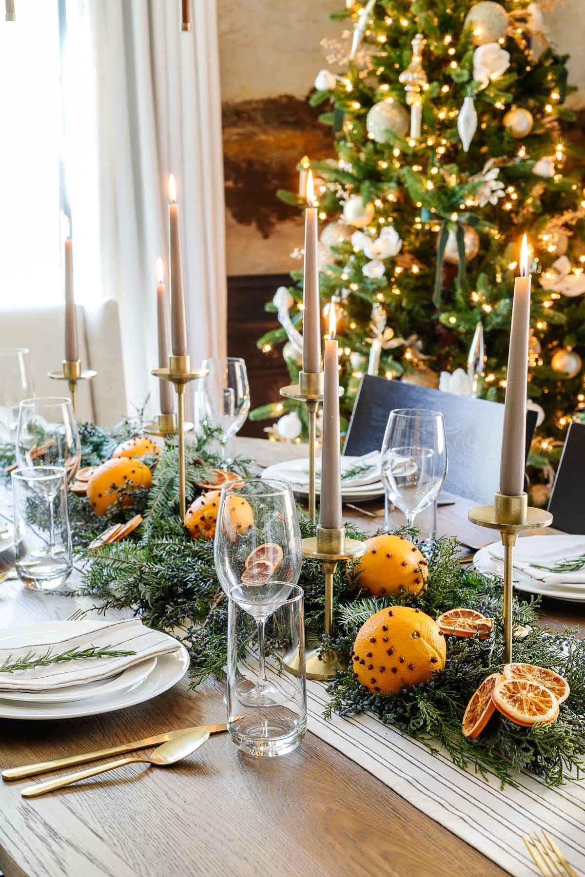 Christmas dining table centerpiece with leaves and dried oranges slices and candlesticks