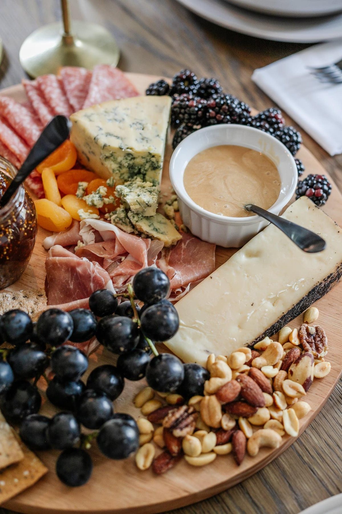 charcuterie board with meats, cheeses, crackers, jams, fruit, nuts, and honey