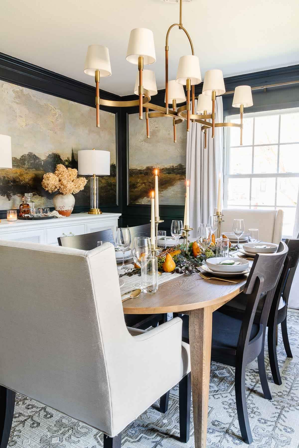 Thanksgiving decor in the dining room with candles, navy walls, and leaves