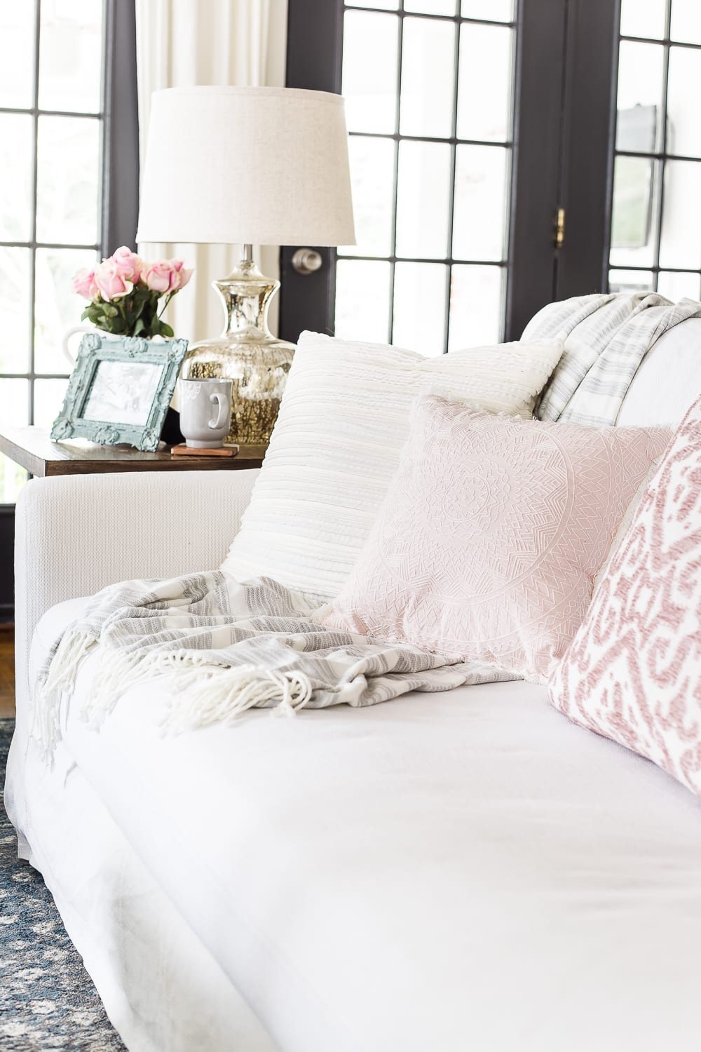 A living room gets a spring refresh with simple florals, candle light, and light fabrics. #springdecor #livingroom #springlivingroom #springaccents #livingroomdesign #livingroomdecor #budgetdecor
