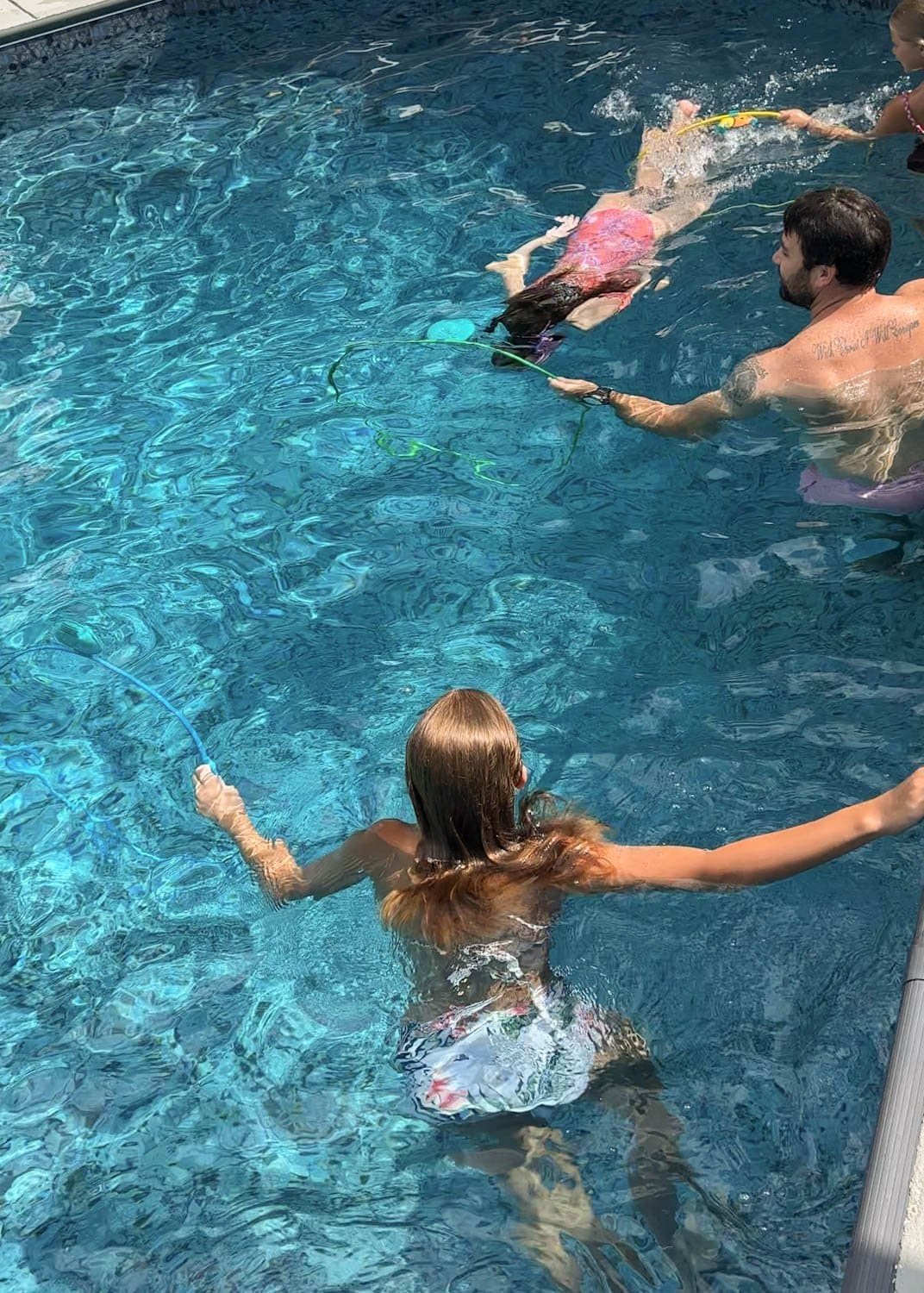 family playing with pool toys using swim through rings