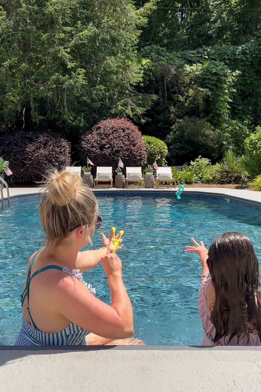 mother and daughter playing with swimming pool toys in a backyard