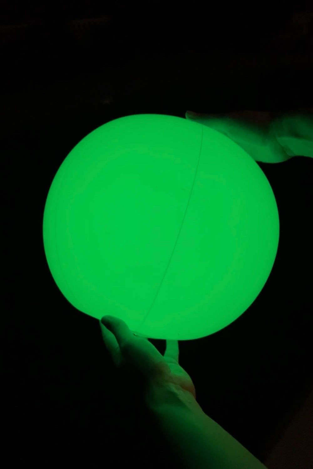 light up beach ball glowing green at night