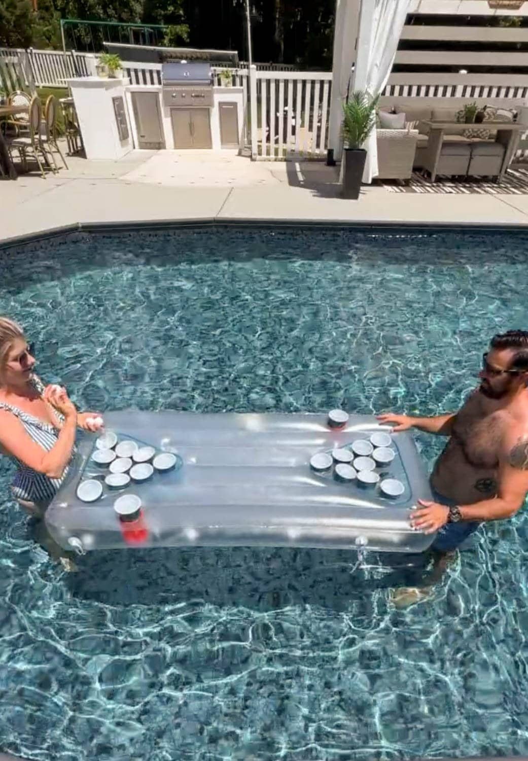 couple playing a beer pong game on a light up pool float