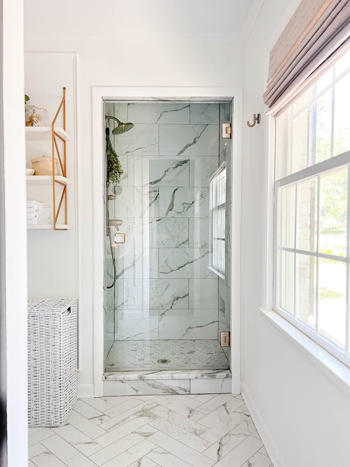 white bathroom with marble shower and frameless glass shower door