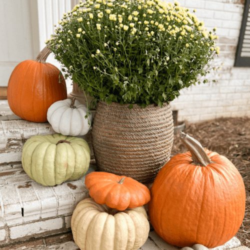 planter of mums and realistic pumpkins on porch