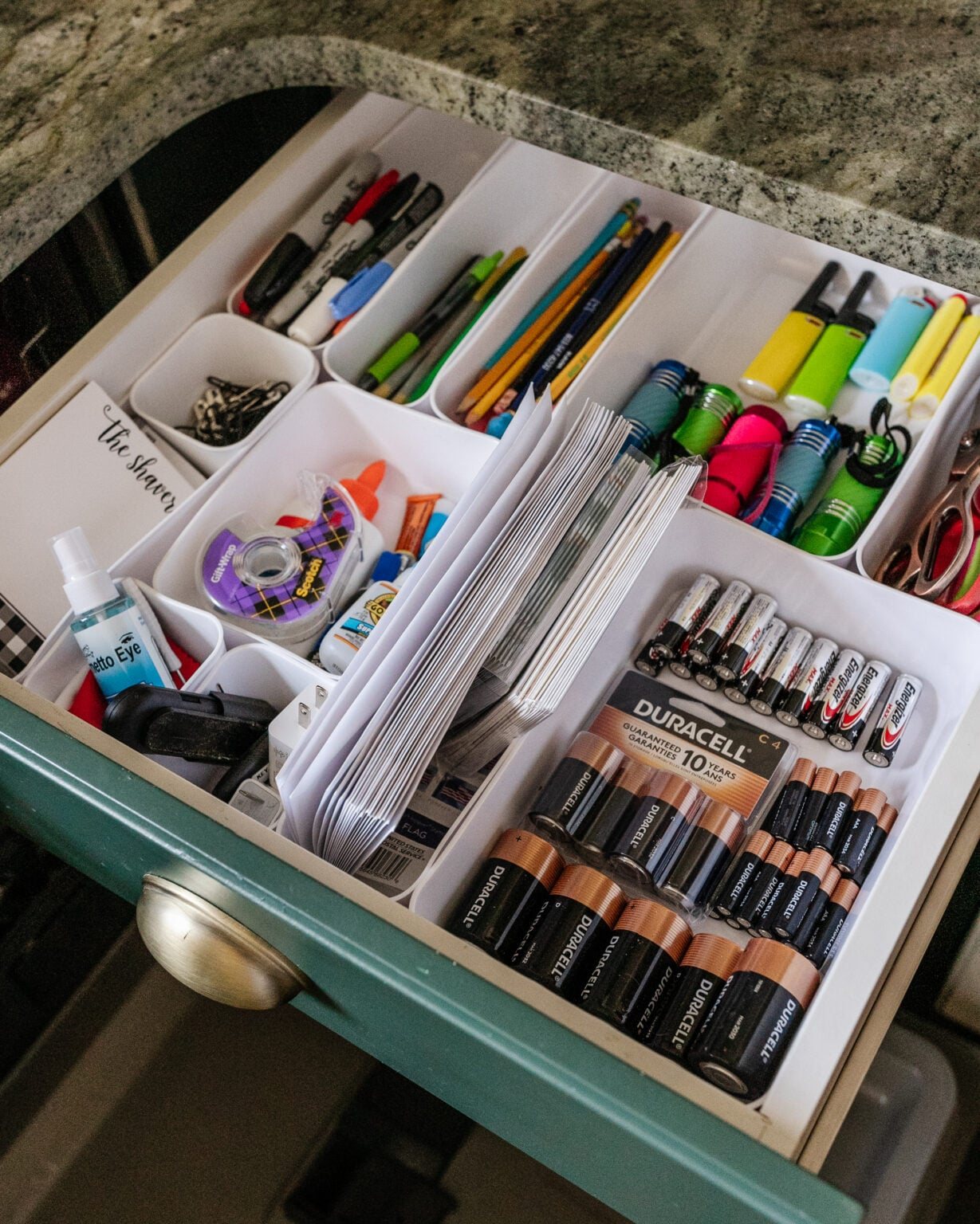 junk drawer organization with batteries, pens, flashlights, lighters, scissors, glue, and tape
