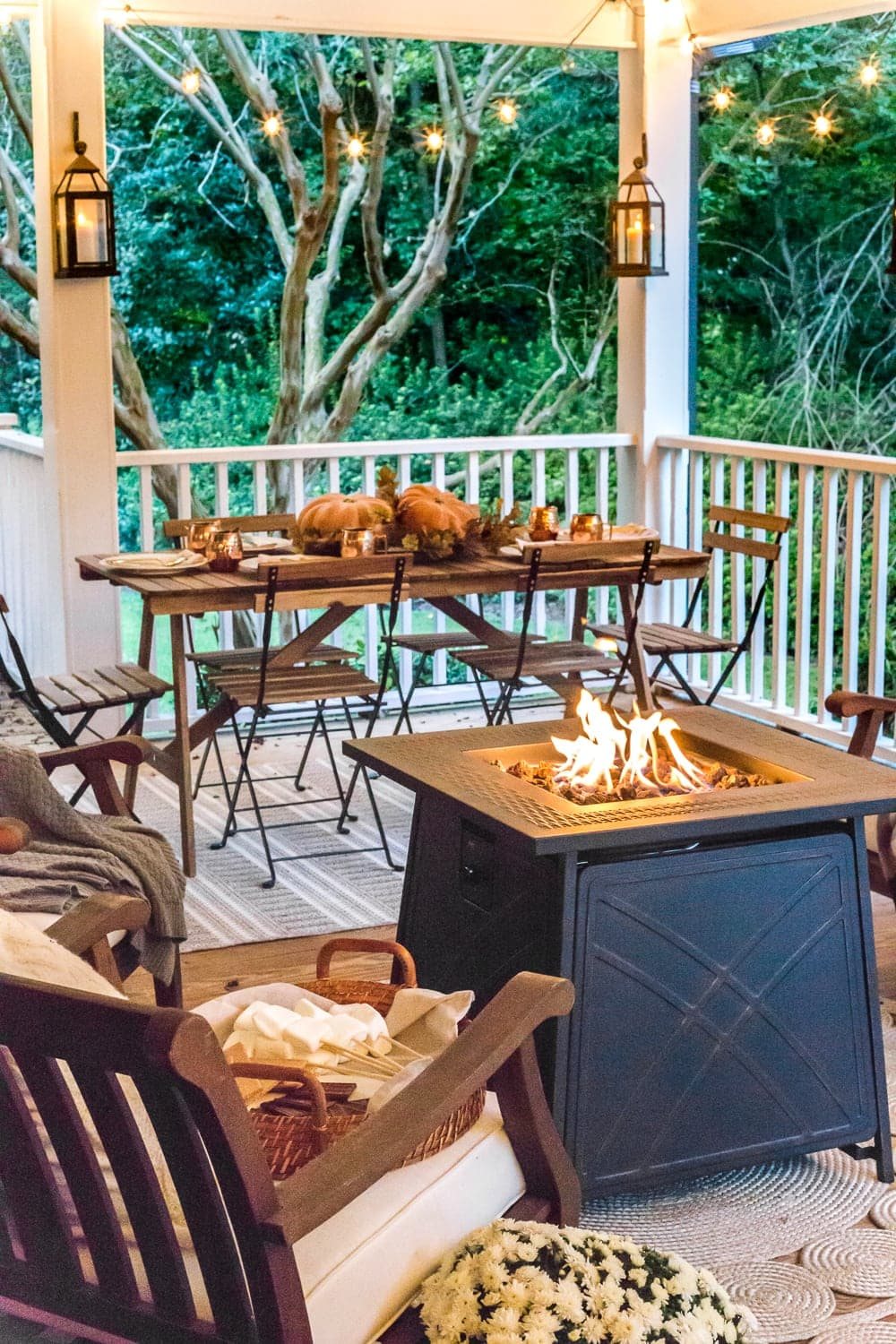 cozy fall porch with fire pit, string lights, and lanterns