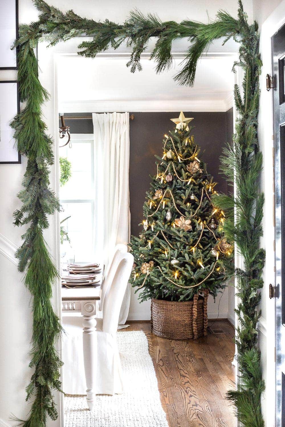 live Christmas tree in dining room and real pine garland surrounding doorway