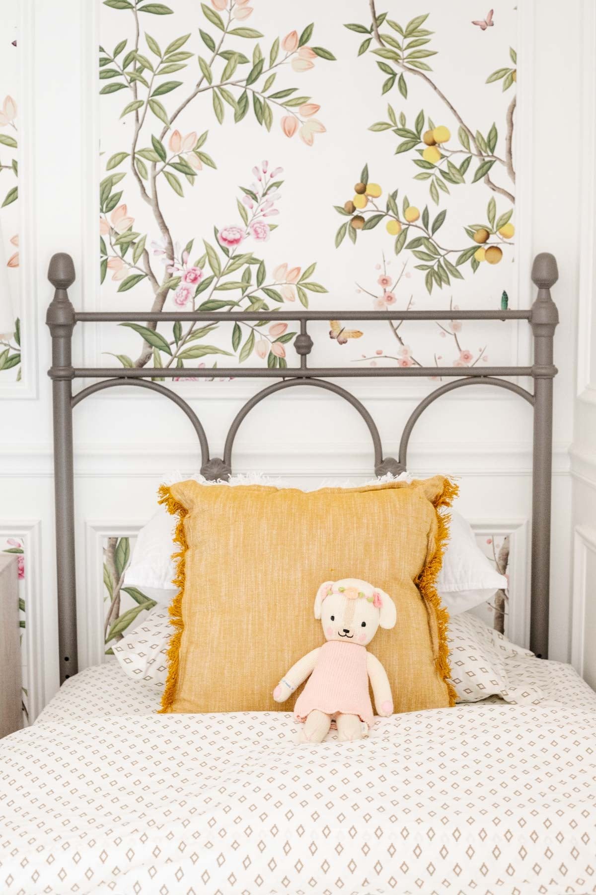 chinoiserie wallpaper in a child's bedroom with picture frame molding and metal bed