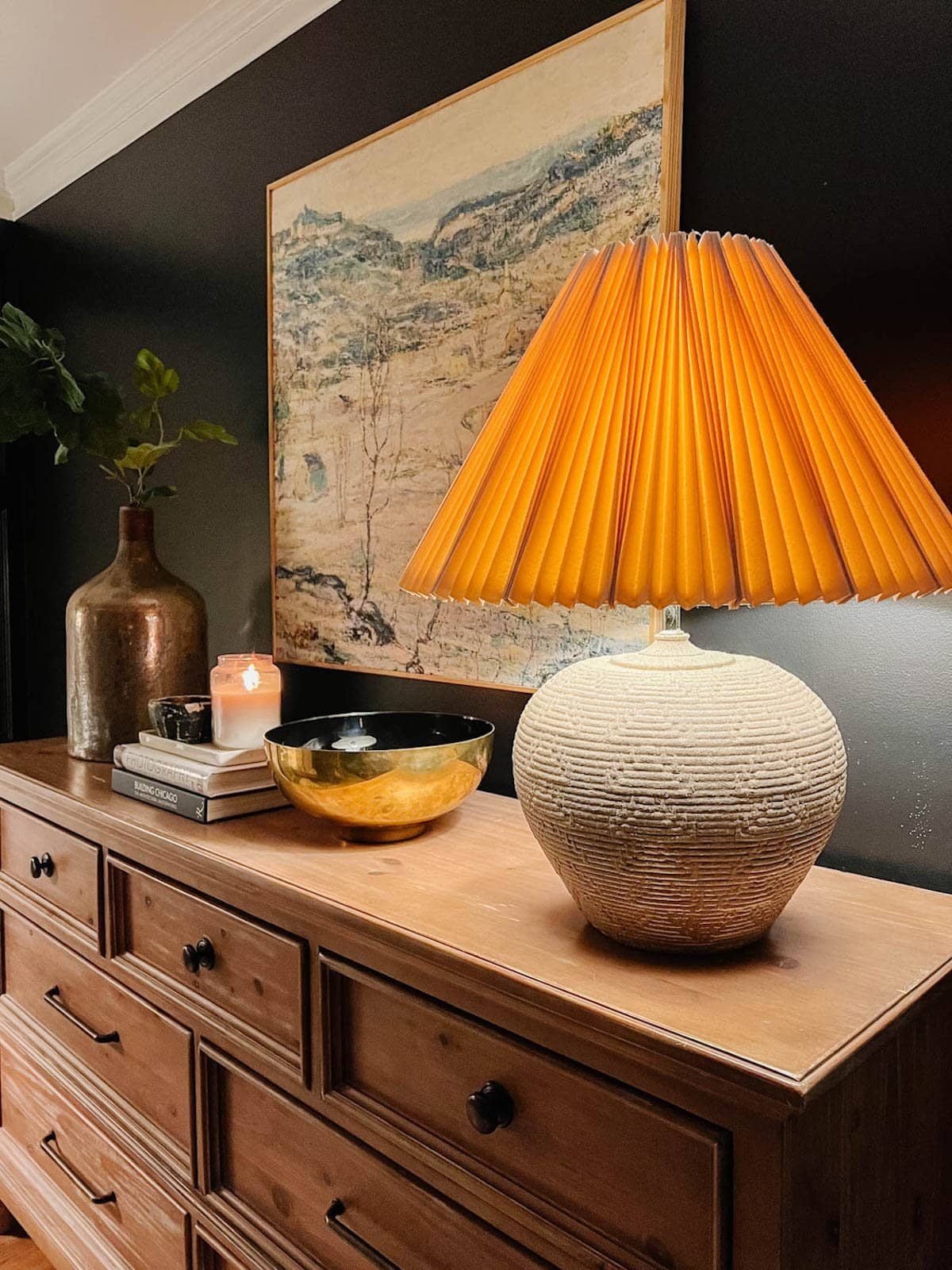 concrete textured rustic table lamp with pleated lamp shade on bedroom dresser with black walls