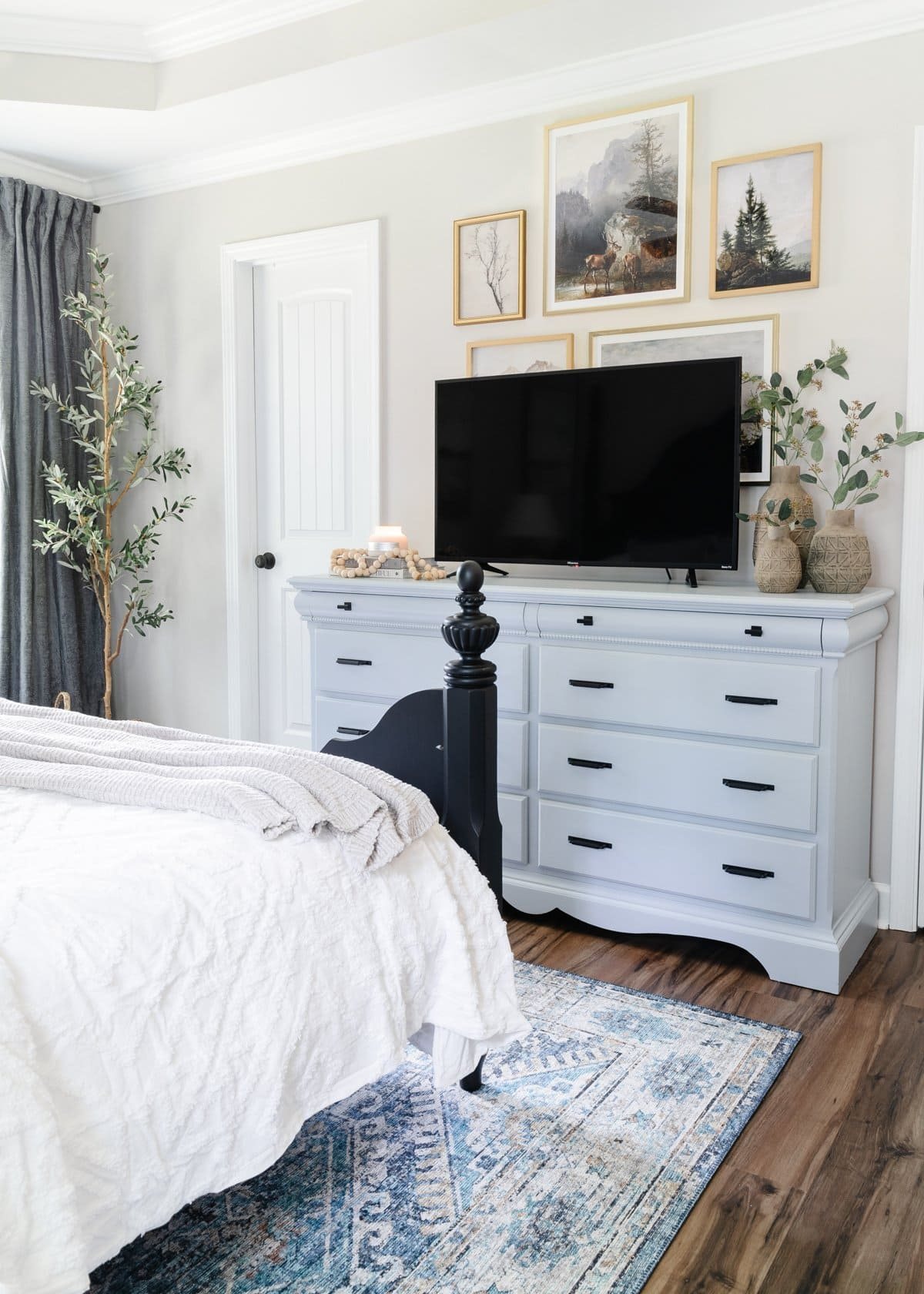 small bedroom with tv on dresser and collected gallery wall decor