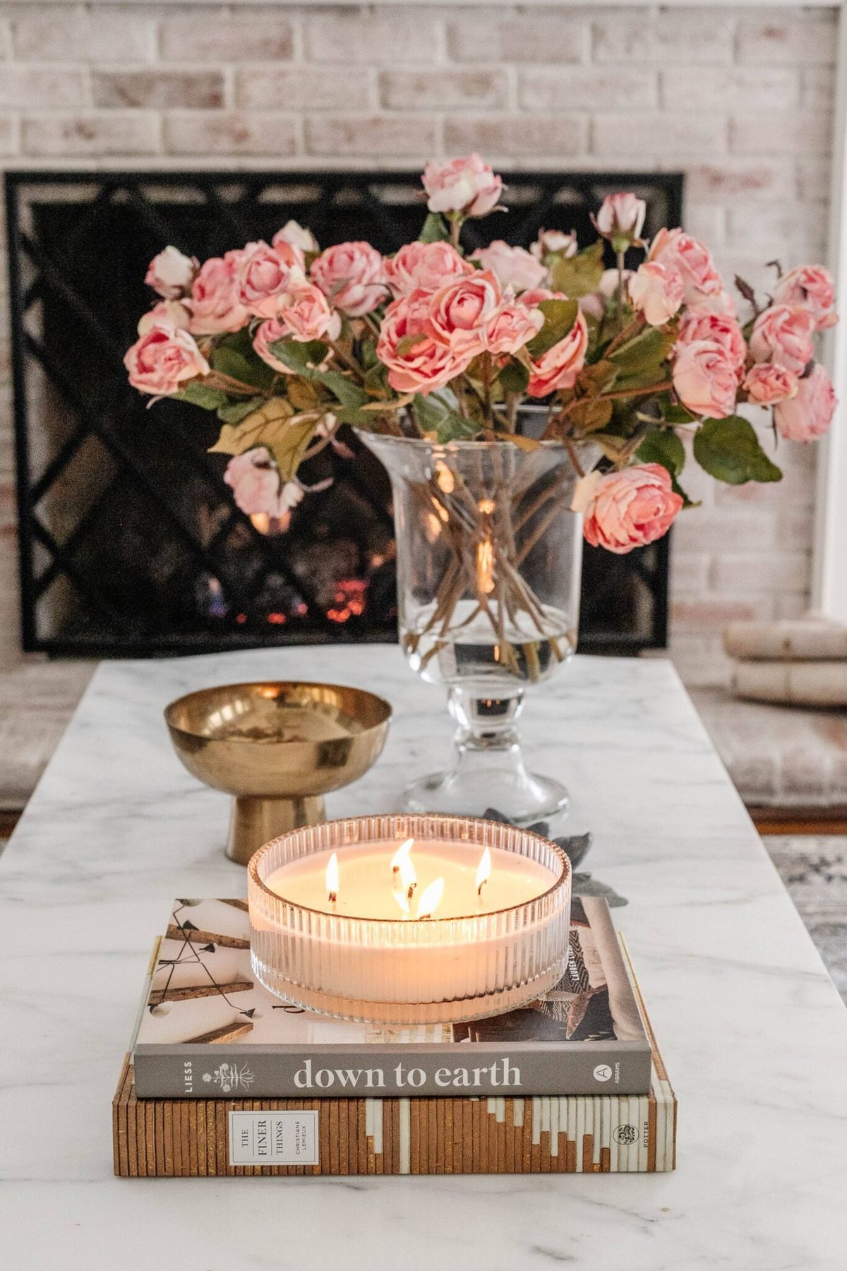 vase of roses, brass bowl, and candle as coffee table decor