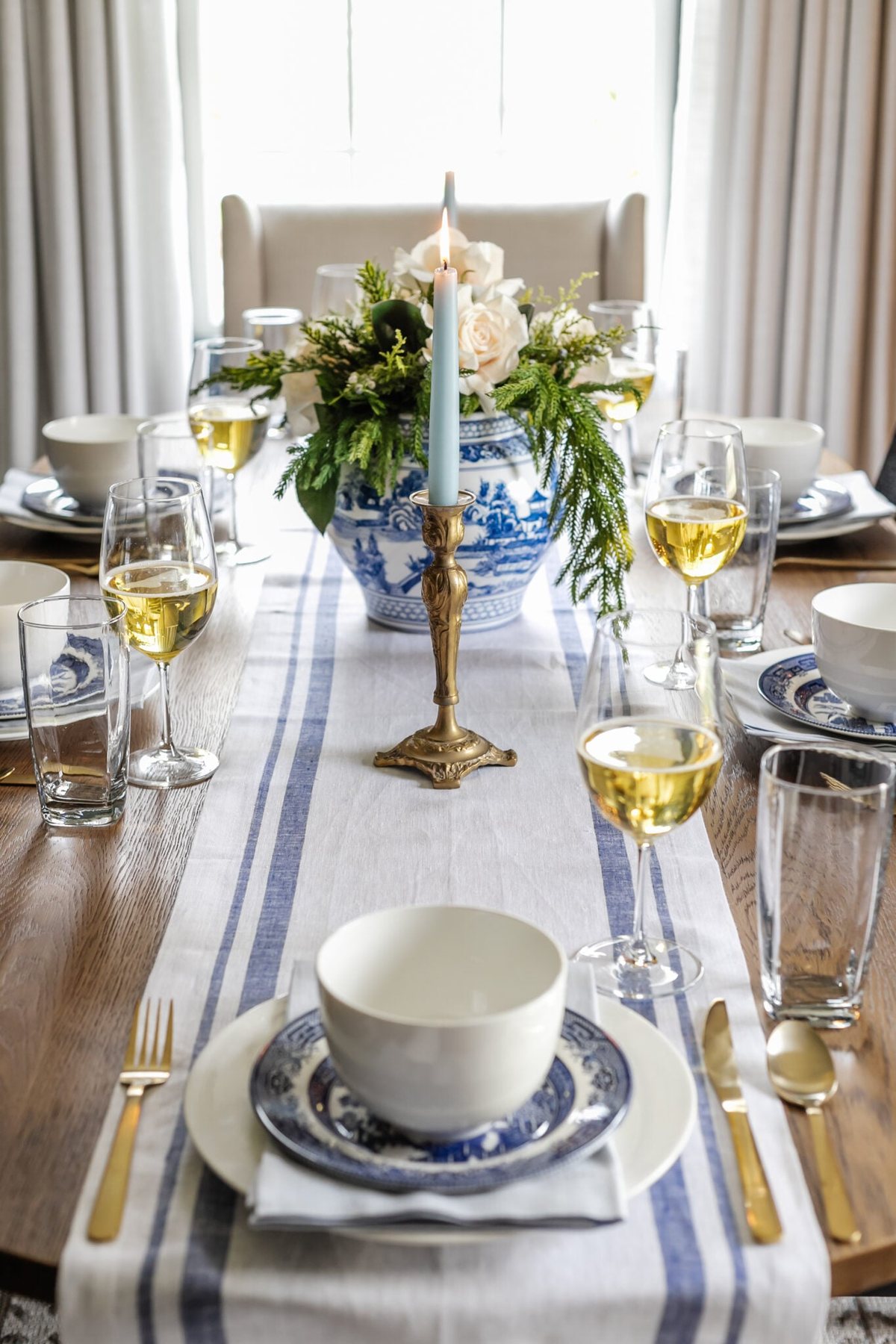 white and blue Christmas dinner table with blue striped runner and blue candles