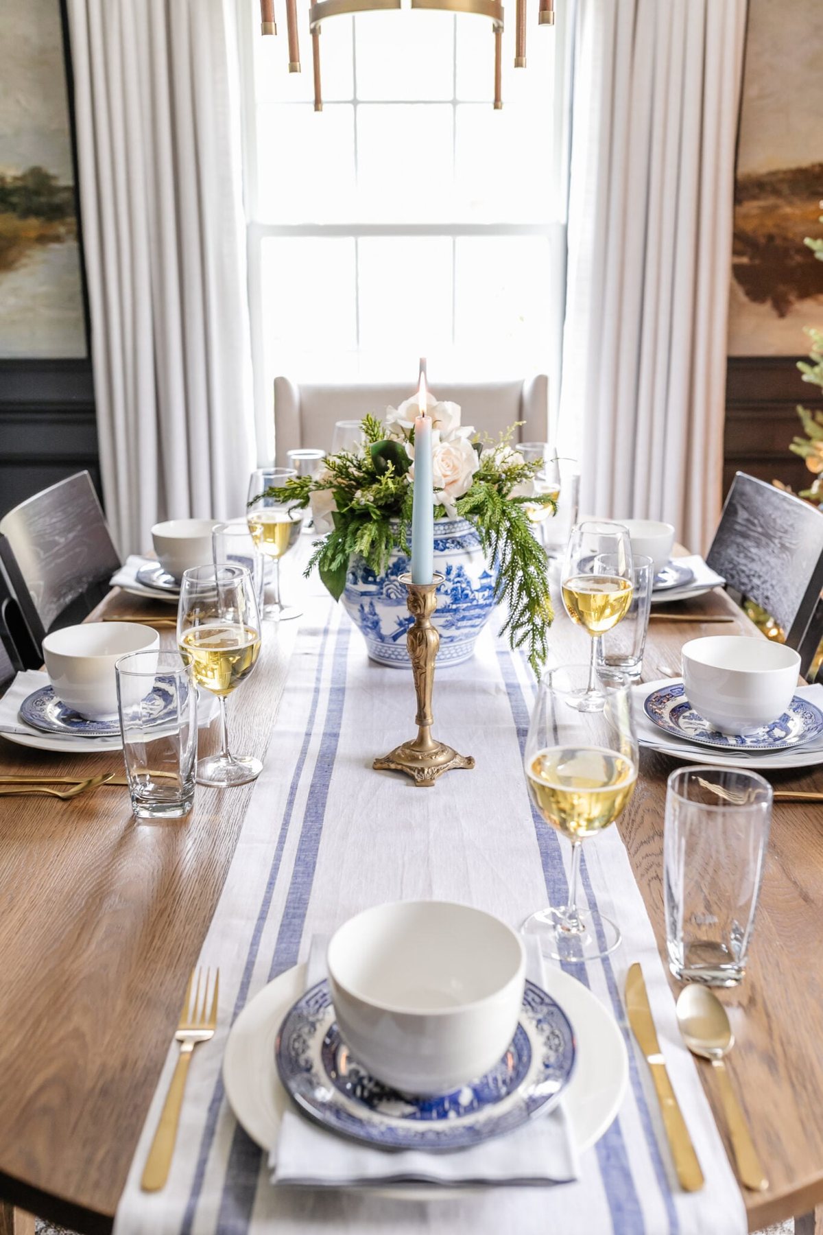 white and blue Christmas dinner table decor with candles, centerpiece, linens, and dinnerware