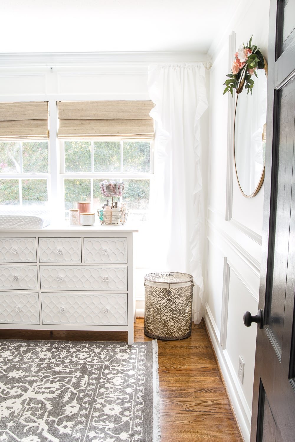 An all white nursery makeover room reveal with classic, vintage style furniture, Anthropologie-inspired patterns and textures, and floral accents.