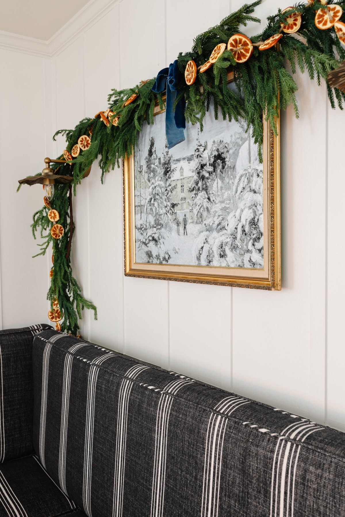 winter painting in gold thrifted frame with pine garland and orange slices