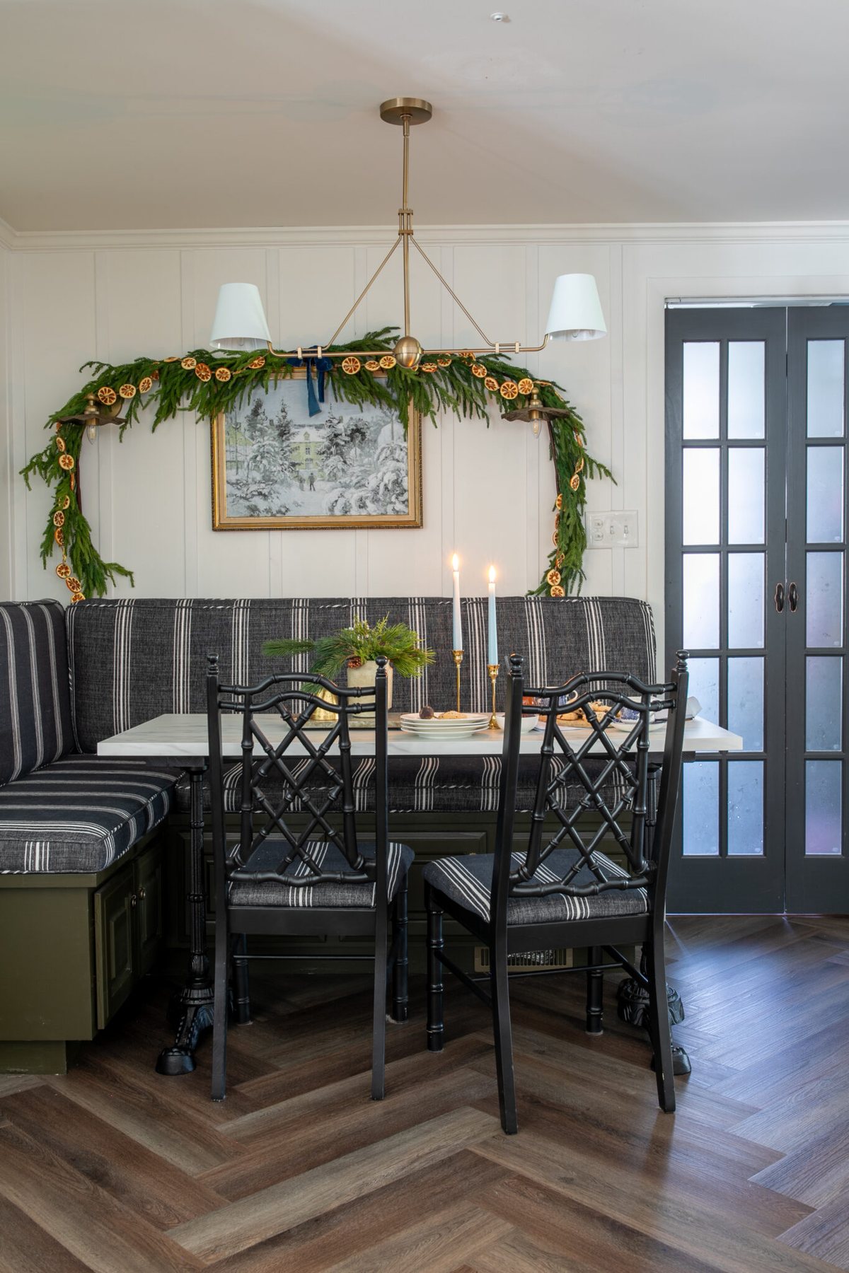 breakfast nook decorated for Christmas with garland and snow art on the wall