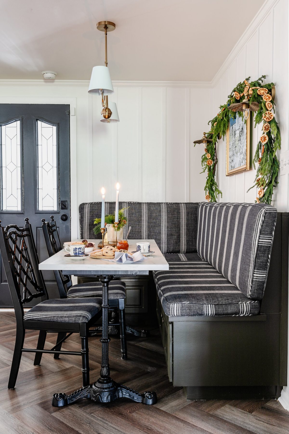 breakfast nook with banquette and kitchen able decorated for Christmas with vase of winter stems