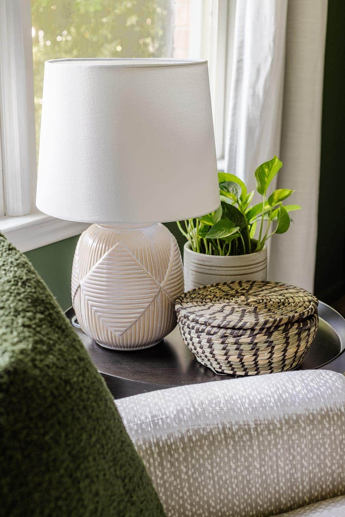 nursery side table with lamp, plant, and lidded basket for holding baby essentials
