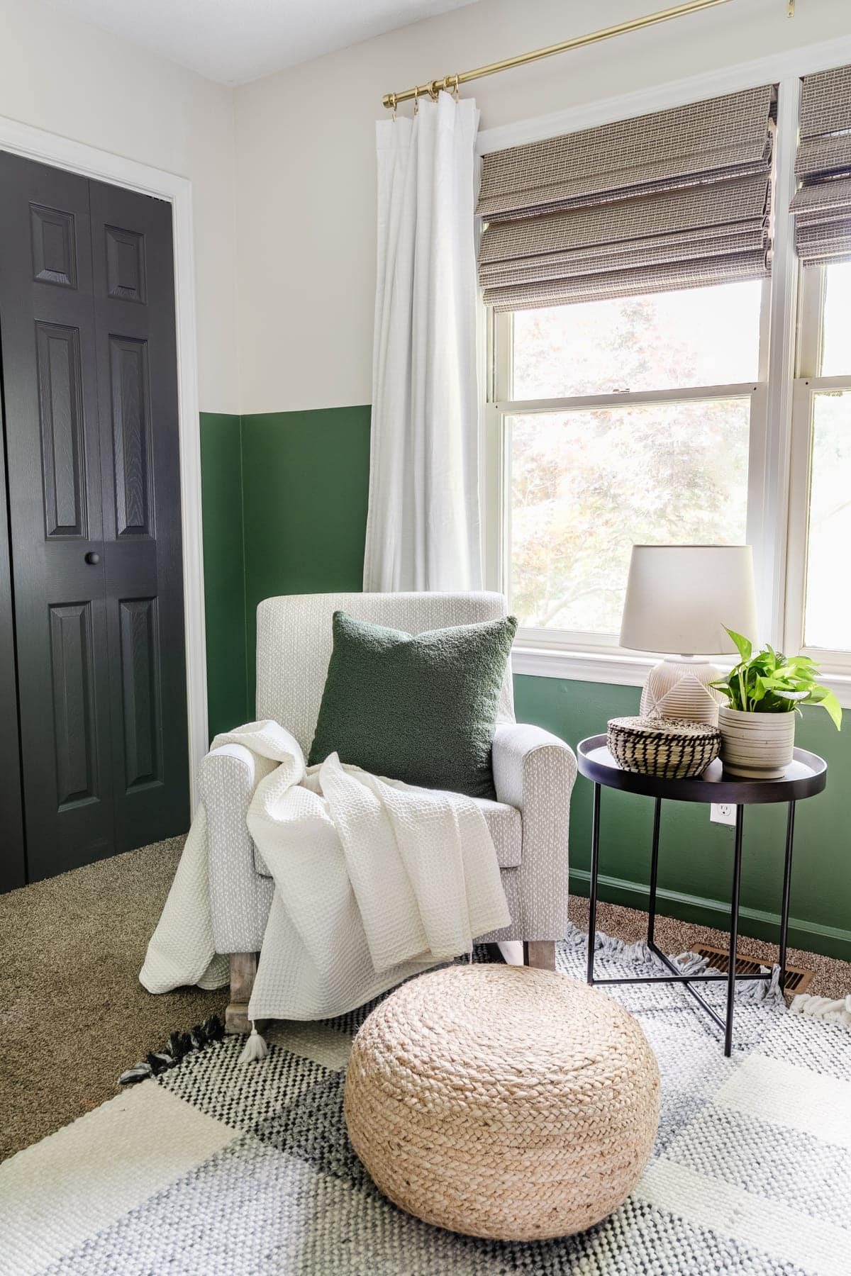 nursery rocker with gray pattern, plaid rug, green paint, blackout curtains, black door, and side table