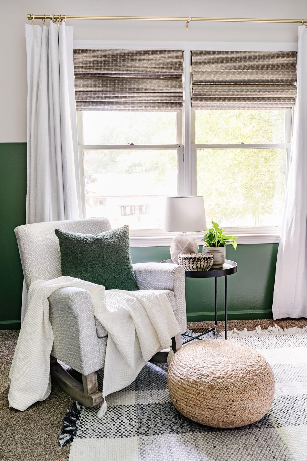 nursery with green paint, plaid rug, and gray rocking chair