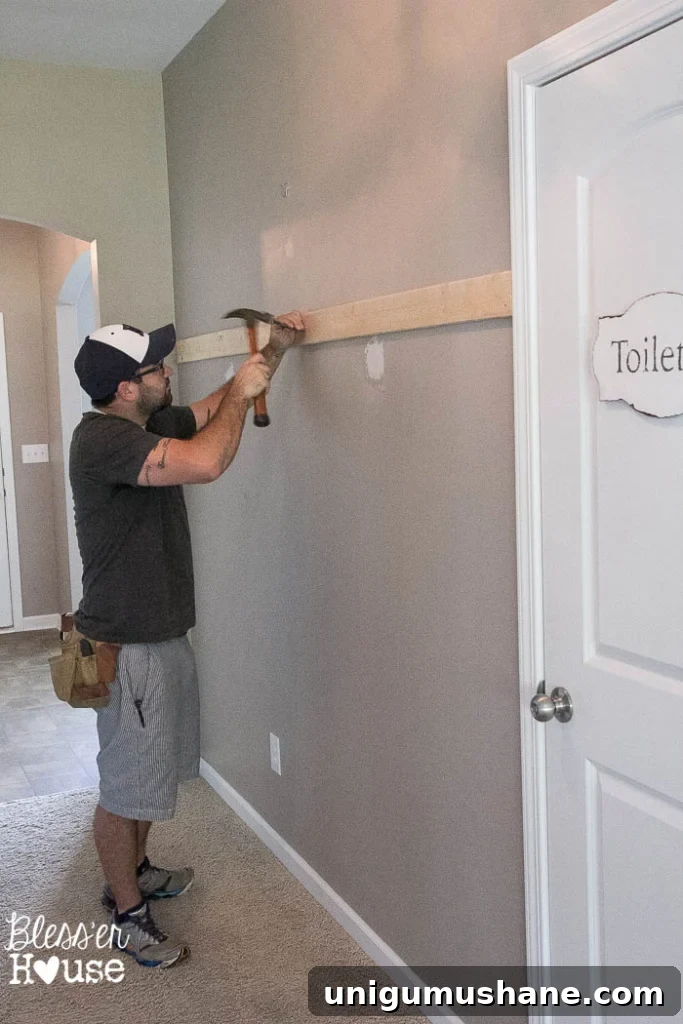 Affordable DIY Board and Batten: Step-by-Step Wall Tutorial 11 nailing board to wall to start board and batten