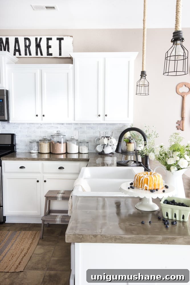 modern farmhouse kitchen with faux brick backsplash, concrete countertops, and white cabinets