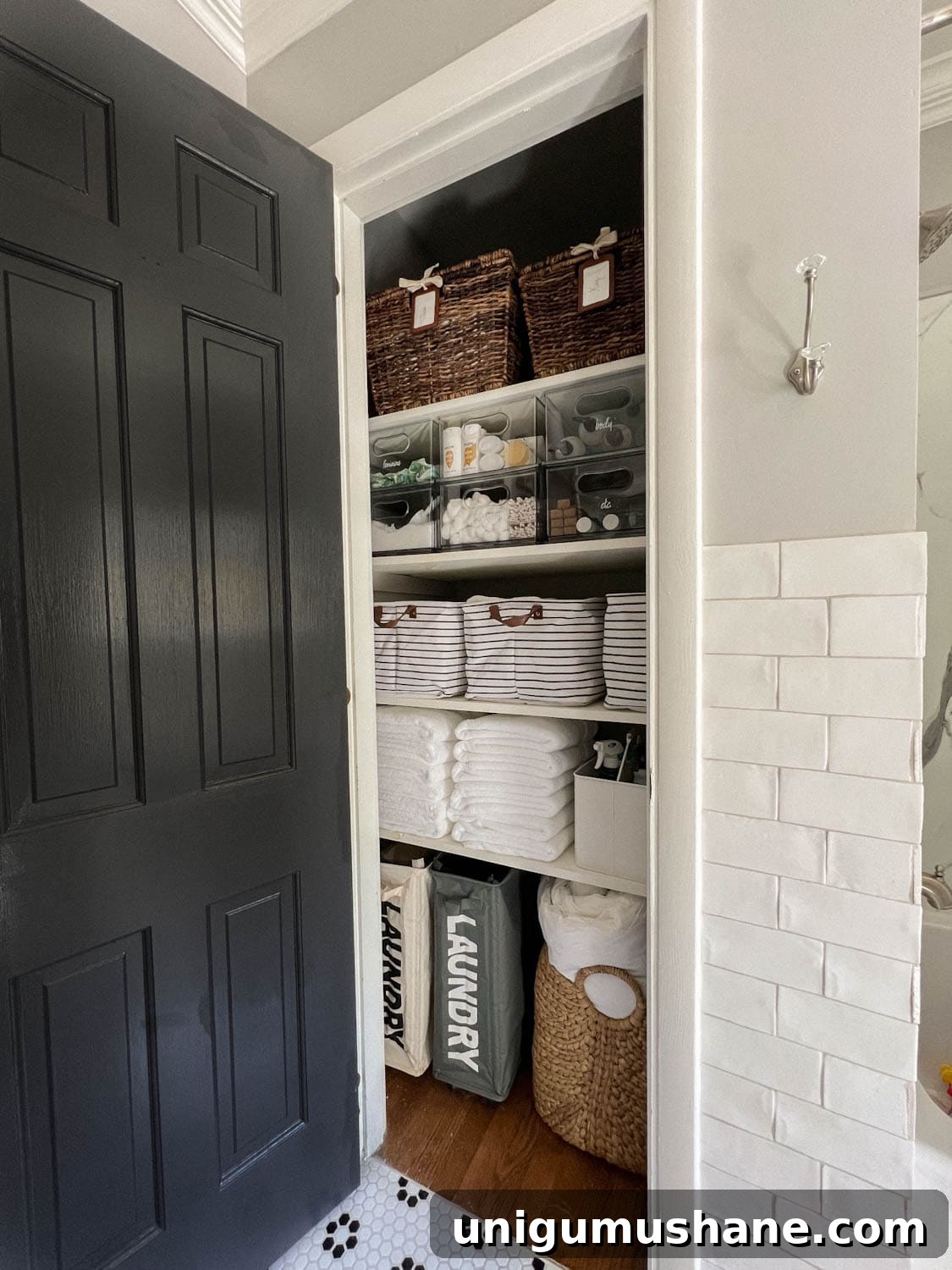 organized bathroom linen closet with bins, baskets, and towels