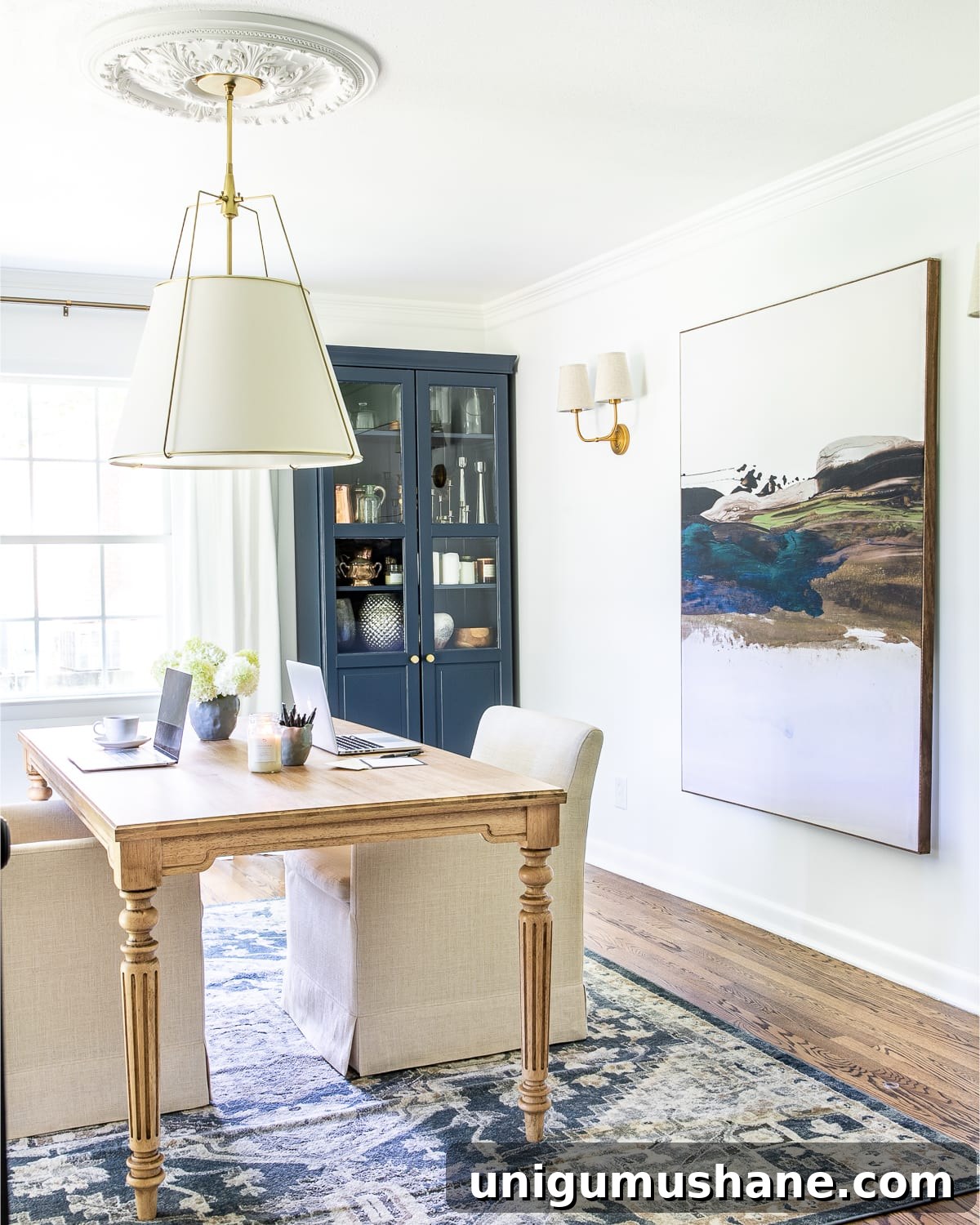 23 Small Room Tricks That Make Any Space Look Bigger 11 home office with oversized art made of a shower curtain, navy blue storage cabinet, and work table with rolling chairs