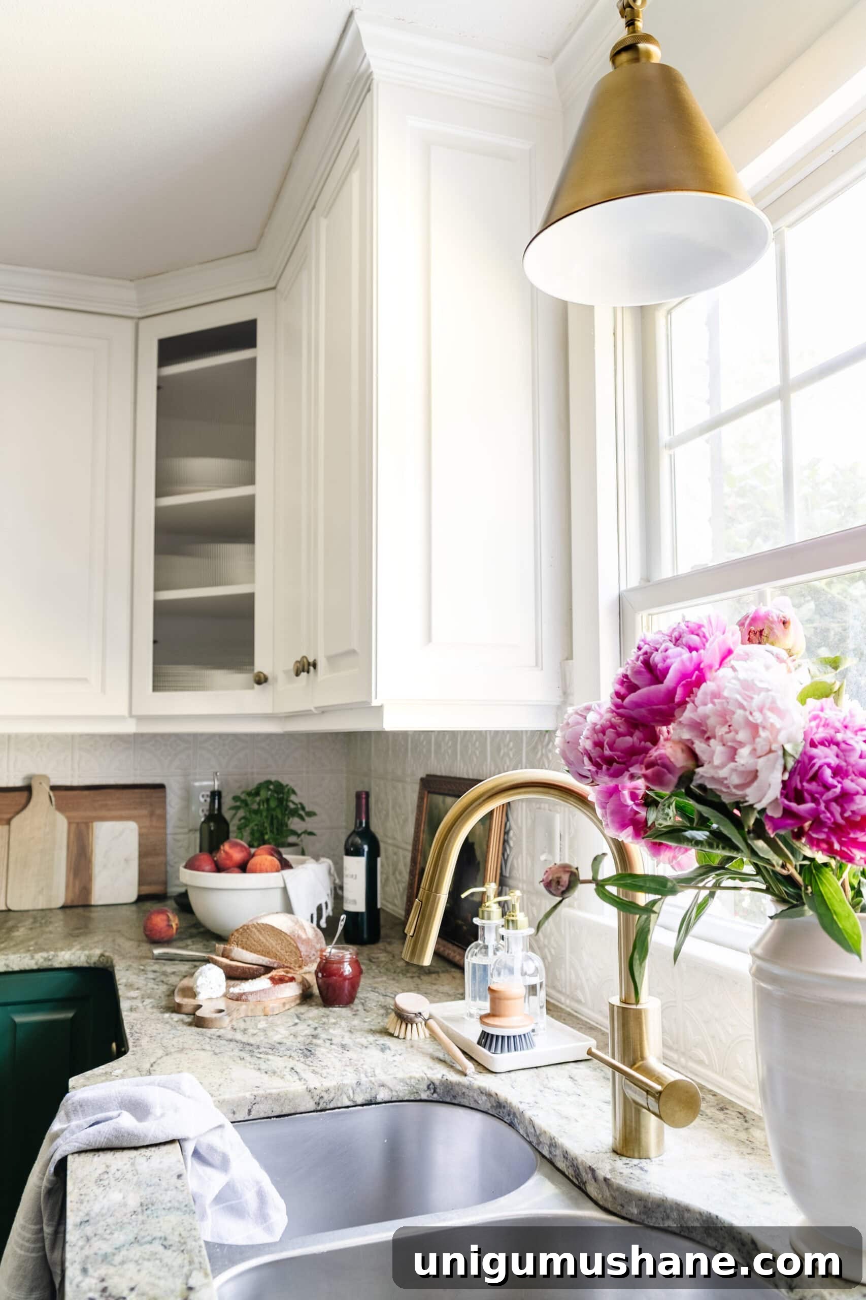 kitchen sink in front of window with brass faucet and brass pendant light