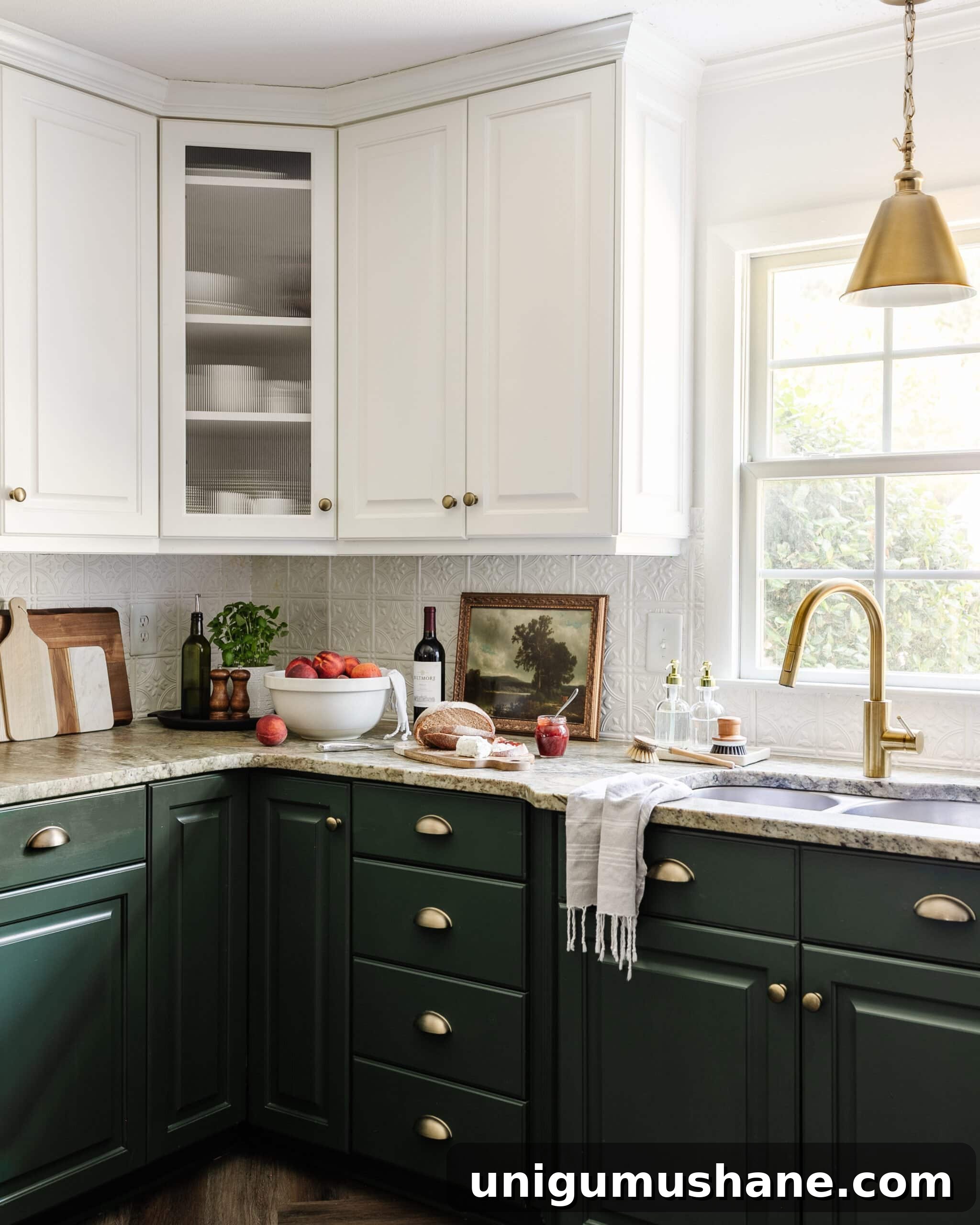leathered granite kitchen countertop, cottagecore style countertop decor, and kitchen sink with brass faucet in front of window