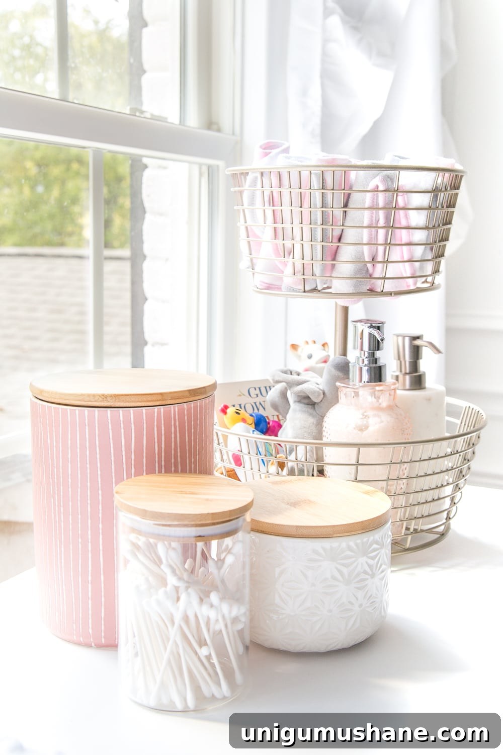 Nursery Organization Tour: Baby Room Storage and Layout 4 Nursery Organization | Use a tiered fruit basket from the kitchenware aisle to store baby washcloths, grabby toys, Wubbanubs, lotion, and hand sanitizer and lidded kitchen canisters to store Q-tips, pacifiers, and hair bows.
