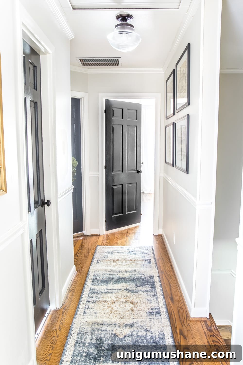 Transform Your Narrow Hallway with Stylish Decor 6 light gray painted hallway with dark charcoal doors, a runner, new lighting, and wall decor