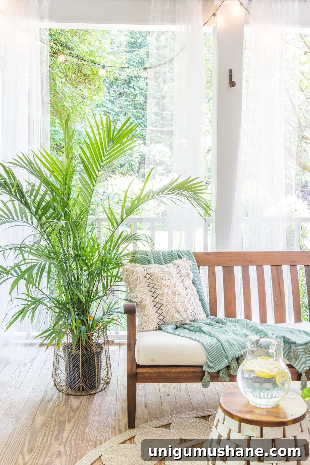 Boho Summer Back Porch Makeover Ideas 5 A tropical boho back porch decorated for summer with breezy, functional style from Flower Home and string lights for evening ambience.
