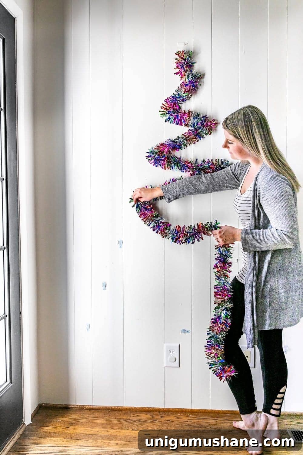 hanging garland on wall hooks to make a DIY Christmas tree on a wall