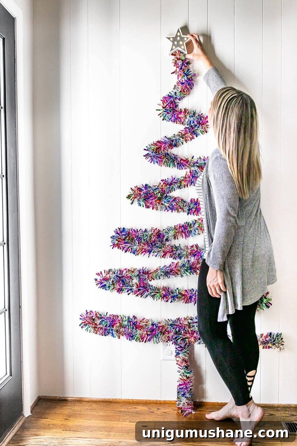 hanging a star on top of garland on a wall