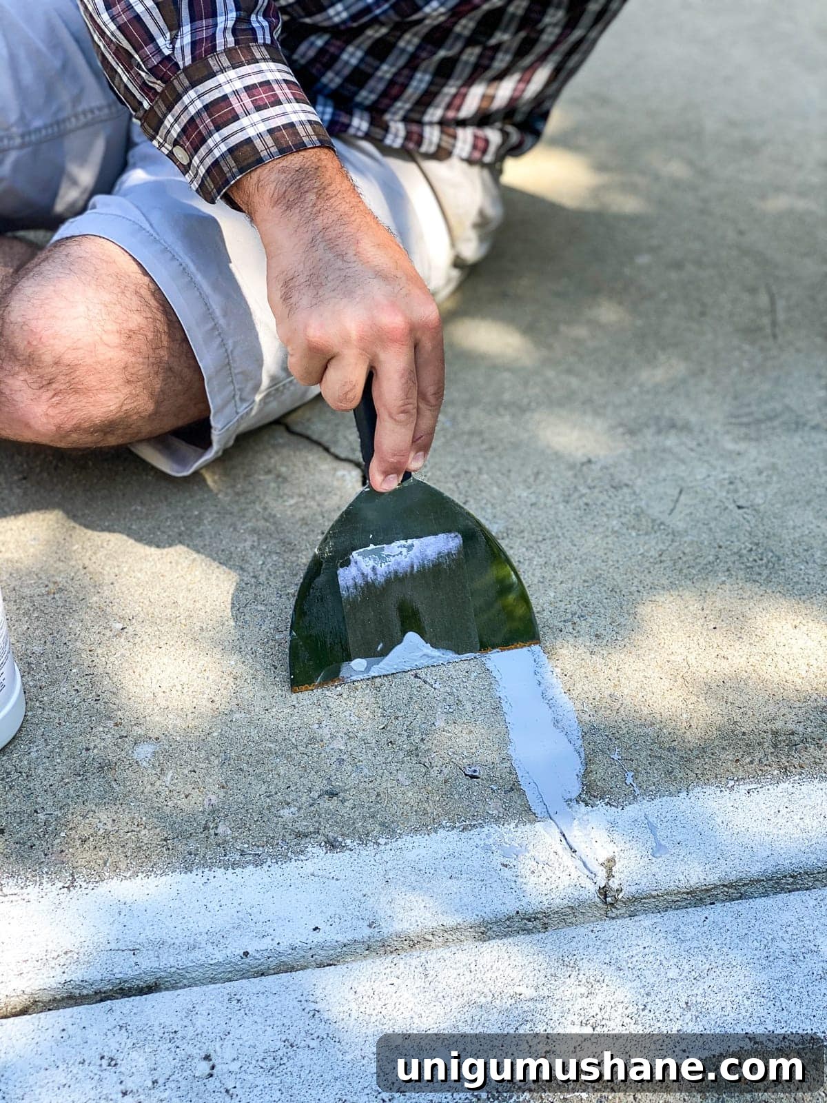 spreading concrete filler to patch cracks and holes