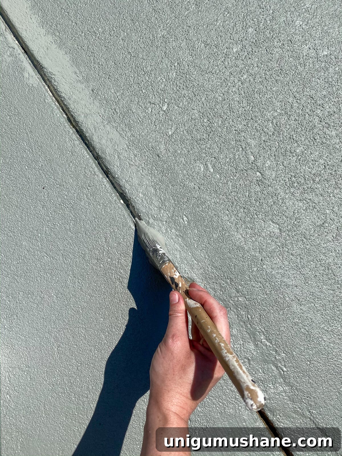 applying concrete paint in cracks and edges to finish a patio