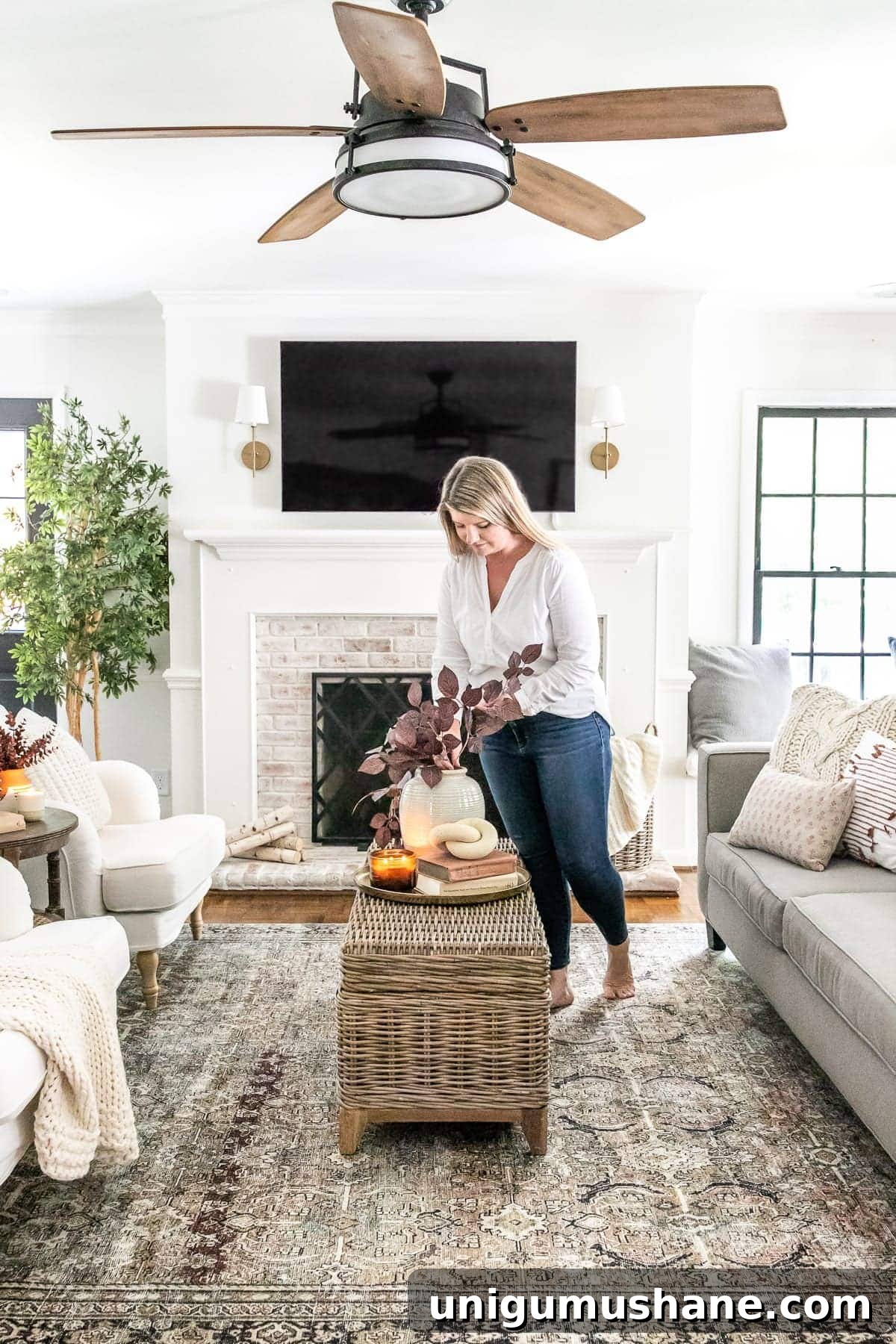 living room decorated for fall with ceiling fan and tv above fireplace