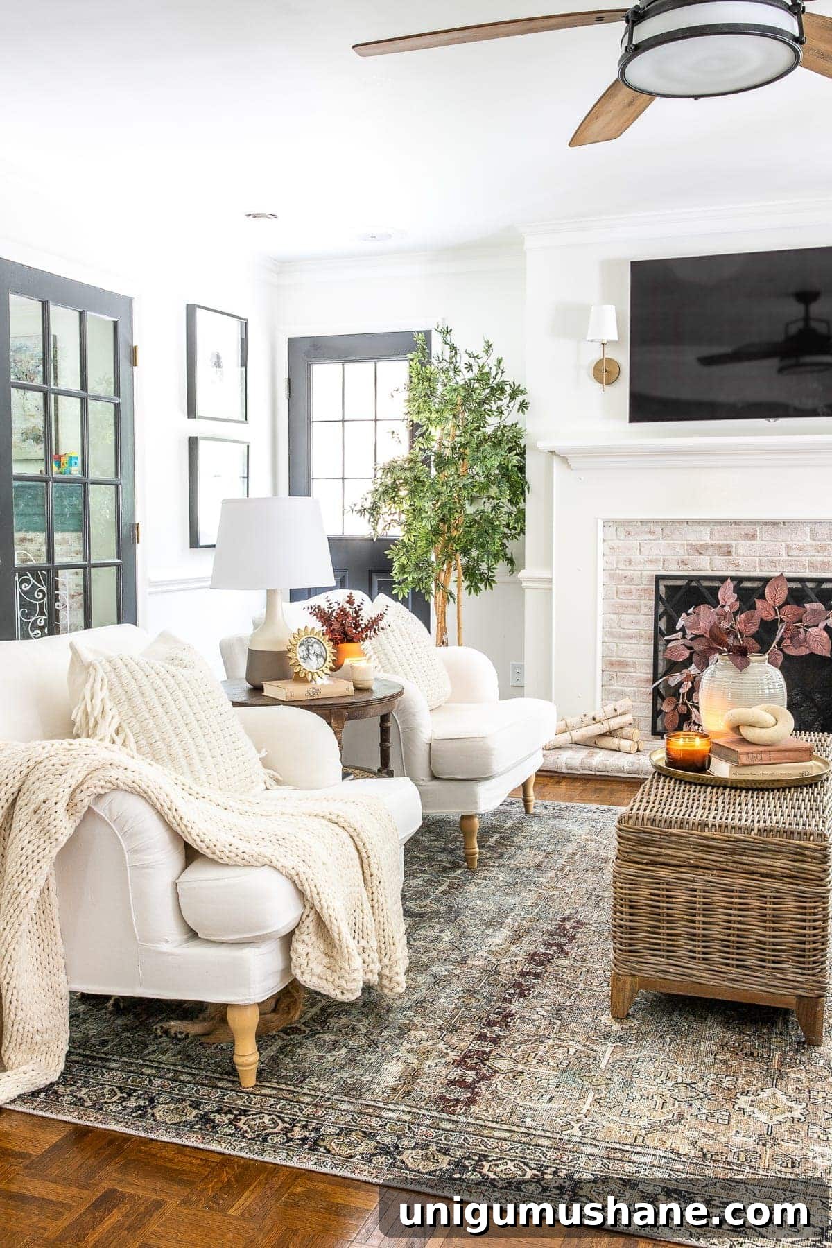 living room decorated for fall with rust and olive vintage style rug ceiling fan and TV above fireplace