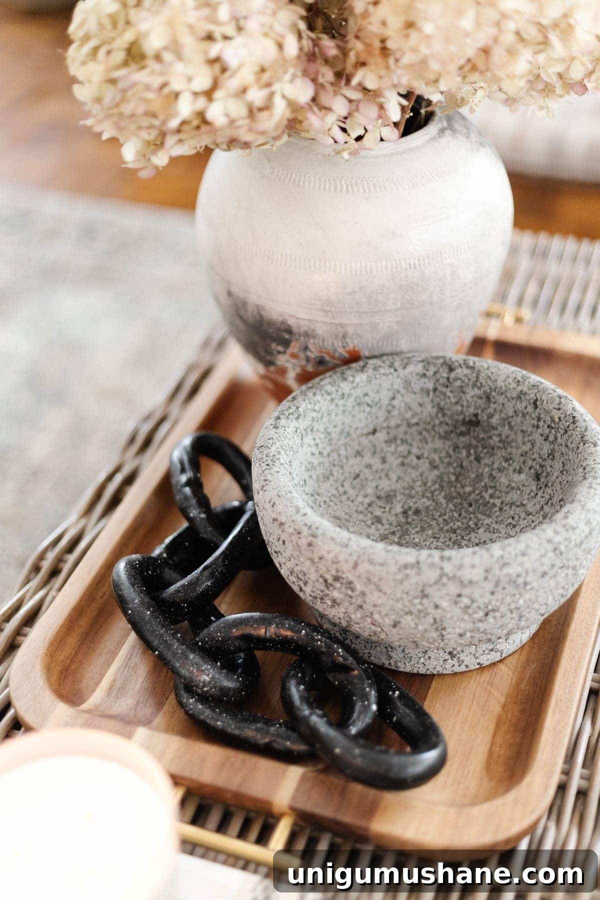 Coffee Table Decor Ideas with Styling Tips 8 decorative chain on a wooden tray with concrete bowl and vase of dried hydrangeas on a coffee table