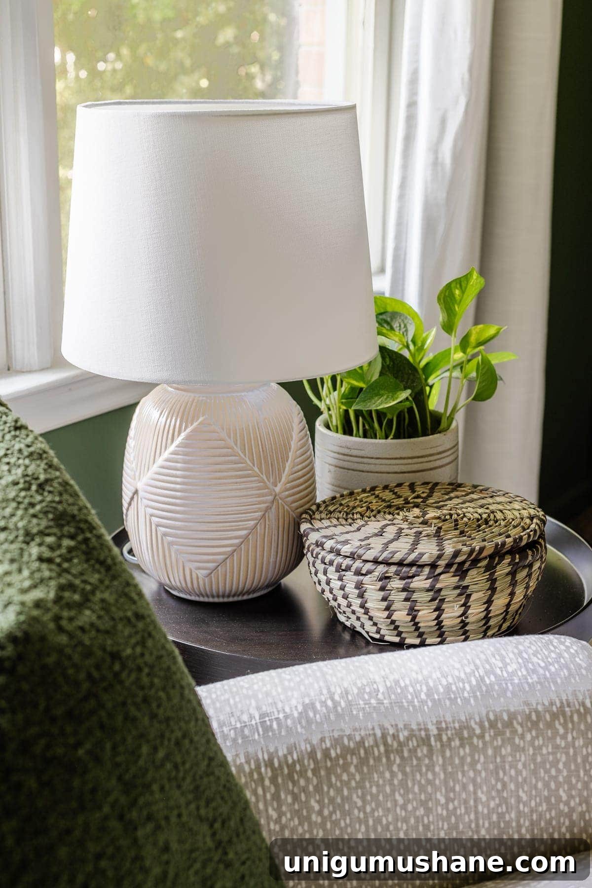 nursery side table with lamp, plant, and lidded basket for holding baby essentials