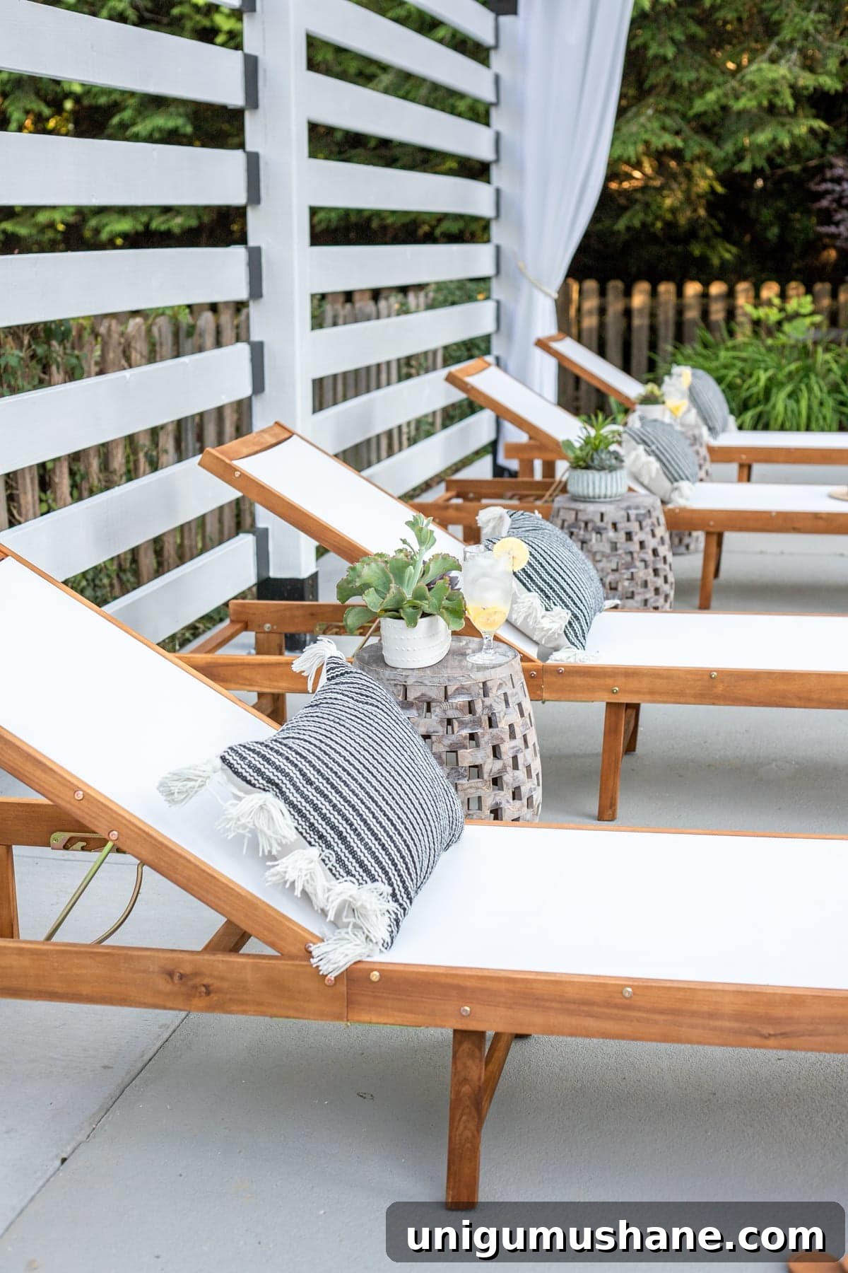 outdoor lounge chairs under white pergola with outdoor curtains and pillows