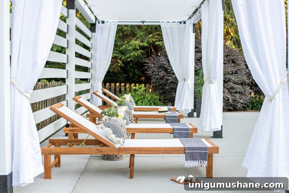 white DIY pergola cabana with outdoor curtains and lounge chairs