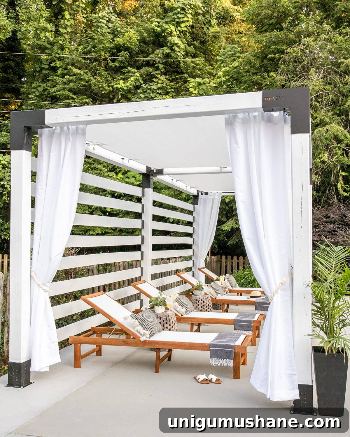 outdoor lounge chairs under a white pergola cabana with outdoor curtains