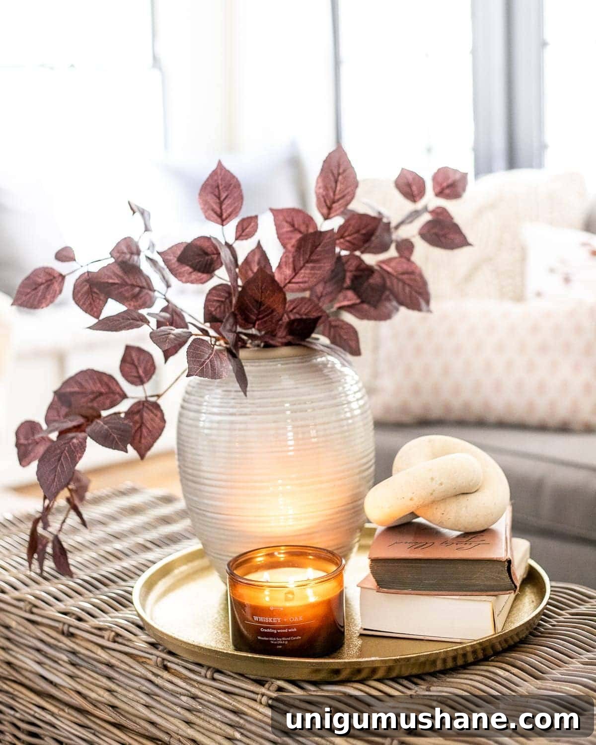 Stylish Fall Home Decor Finds Under $40 2 fall decor on a coffee table with brass tray, amber glass candle, wood knot, books, and vase with autumn stems