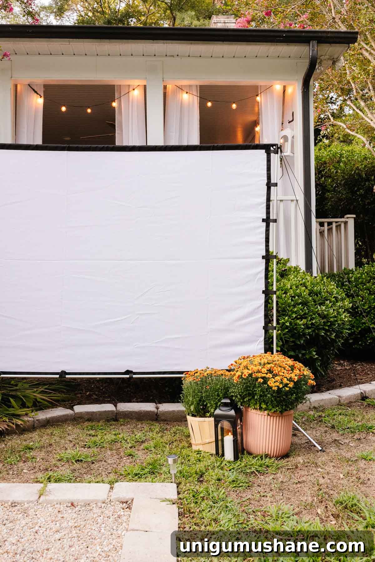 outdoor fall decor - garden mums and lanterns around outdoor movie screen for backyard party