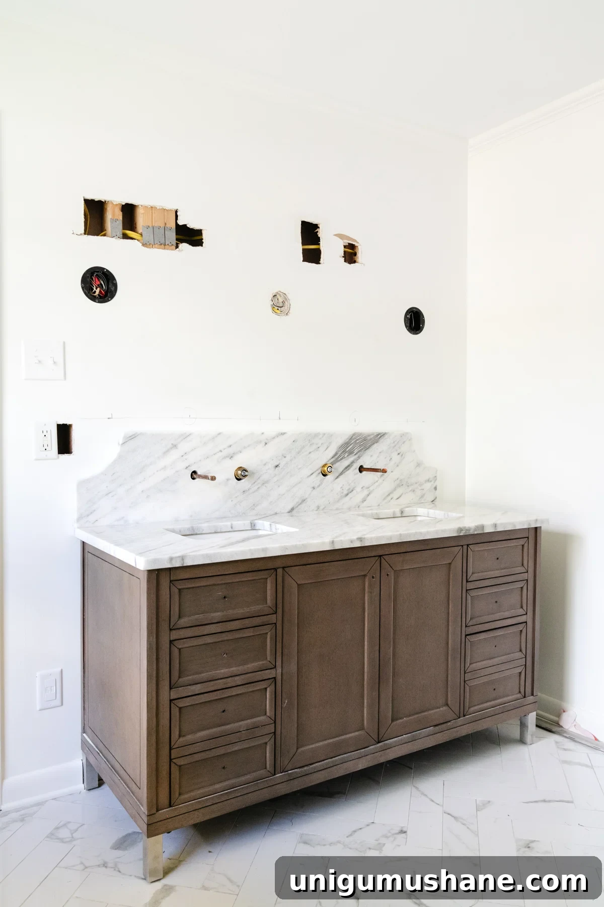 wood double vanity in a bathroom with scalloped marble backsplash and herringbone tile floor