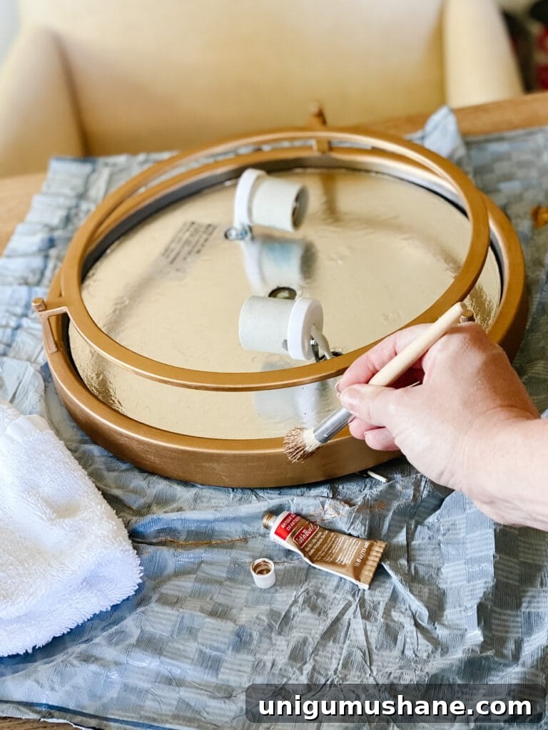 How to Upcycle a Sunburst Mirror into a Stunning Light Fixture 8 painting rub n buff on a light fixture